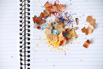 High angle view of multi colored pencil shavings on book