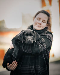 Woman holding dog while standing outdoors