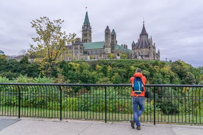 Rear view of man standing by bridge against sky
