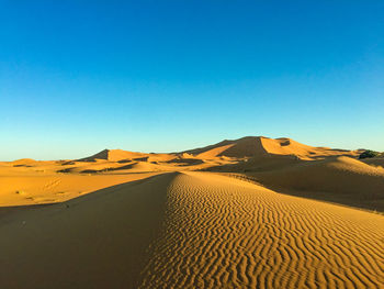 Scenic view of desert against clear blue sky