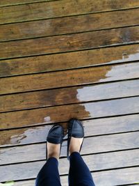 Low section of woman standing on wet wooden walkway