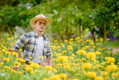 Portrait of smiling woman standing by flowering plants