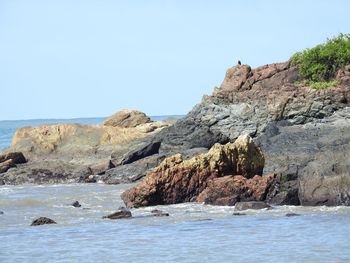 Rock formations on sea shore against clear sky