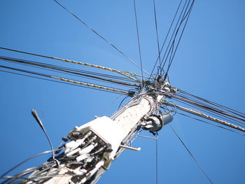 Low angle view of electricity pylon against blue sky