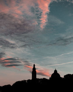 Silhouette of building against cloudy sky at sunset