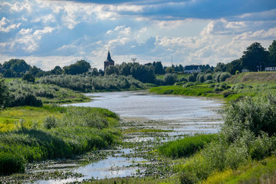 Scenic view of river by building against sky