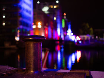 Close-up of illuminated lamp on table by river in city at night