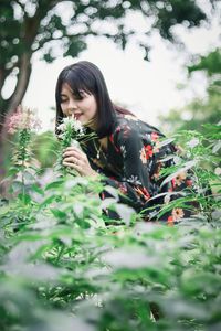 Young woman touching flowers on plants