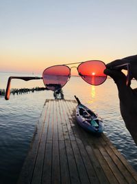 Reflection of person in lake against clear sky during sunset