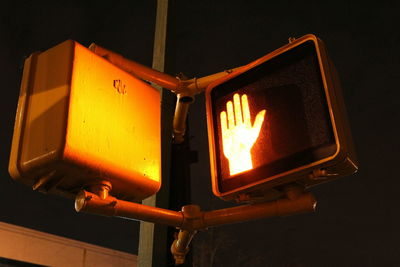 Low angle view of illuminated hand sign at night
