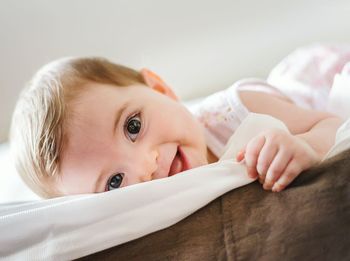 Close-up portrait of cute baby girl lying on bed at home