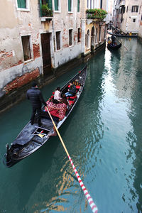 High angle view of gondola in venetian canal along buildings