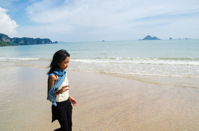 Young woman standing on beach against sky