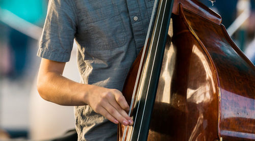 Midsection of man playing double bass