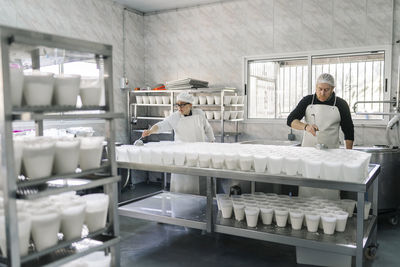 Chefs preparing cheese in containers at kitchen