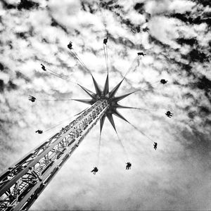 Low angle view of ferris wheel against cloudy sky