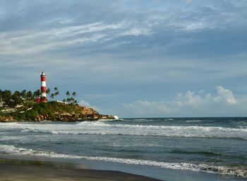 Lighthouse by sea against sky