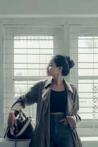 Side view of young woman standing against building