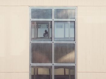 Digital composite image of man and woman standing by window of building