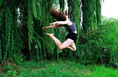 Woman jumping over grass in park