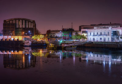 Illuminated buildings against clear sky at night