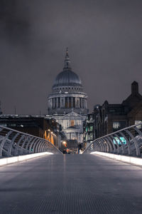 Illuminated bridge leading towards cathedral against sky at night