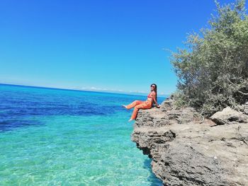 Man in sea against clear blue sky