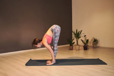 Young woman doing yoga on yoga mat in atmospheric yoga studio