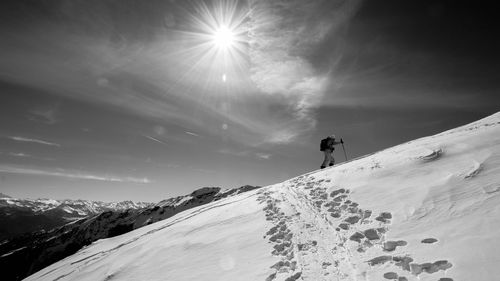 Low angle view of man hiking on snowcapped mountain against sky