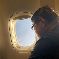 Portrait of man looking through airplane window