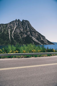 Empty road by mountain against clear sky