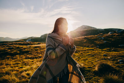 Woman with shawl standing on mountain against sky