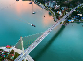 Aerial view of bridge over bay in city during sunset