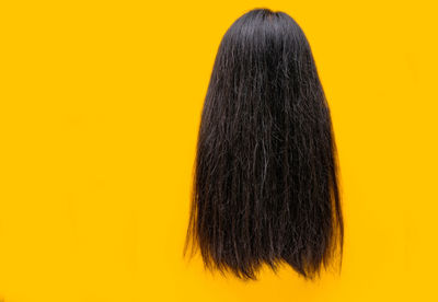 Rear view of woman against yellow background