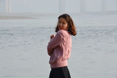 Portrait of smiling woman standing by sea