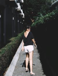 Rear view portrait of woman looking over shoulder while walking on footpath