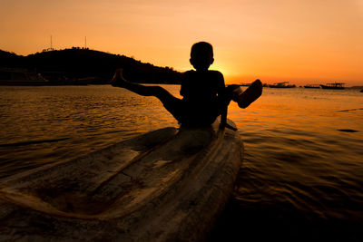 Rear view of silhouette man at beach during sunset