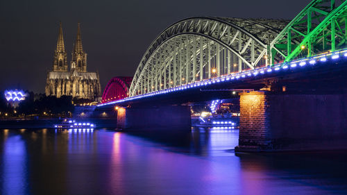 Illuminated bridge over river at night