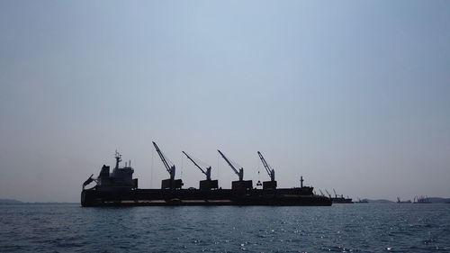 Cranes at commercial dock against clear sky