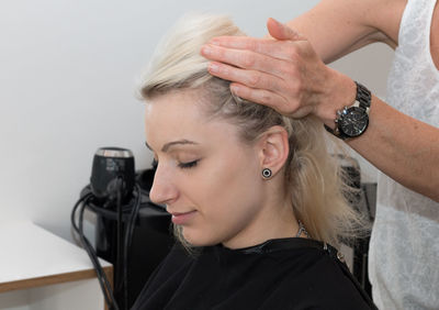 Midsection of hairdresser styling hair for young customer