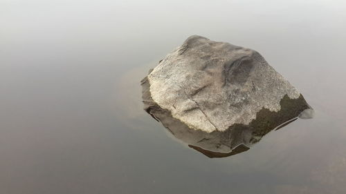 Close-up of reflection of rock in water against sky