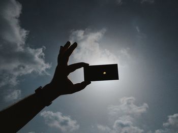 Low angle view of person hand against sky during sunset