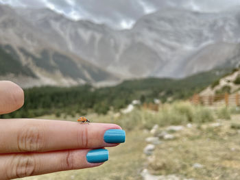 Close-up of hand holding umbrella against mountain