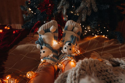 Female feet in a cozy knitted teddy bear socks on the background of the christmas tree. new year