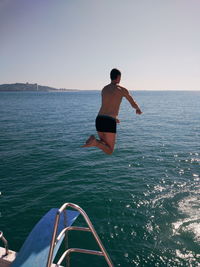 Rear view of shirtless man on sea against sky