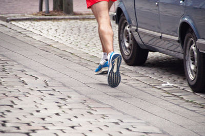 Low section of athlete running marathon on street