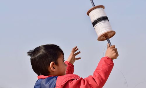 Close-up of boy playing against clear blue sky