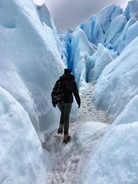 Rear view of woman walking by snow covered landscape