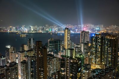 Illuminated modern buildings in city against sky at night