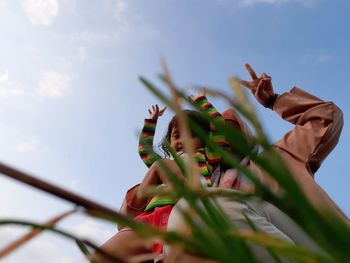 Low angle view of siblings on plant against sky